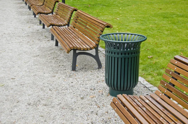 Garbage bin and wooden bench in city park — Stock Photo, Image