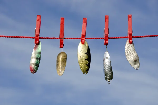 Various vintage metal lures - spoons on cloth string and sky — Stock Photo, Image