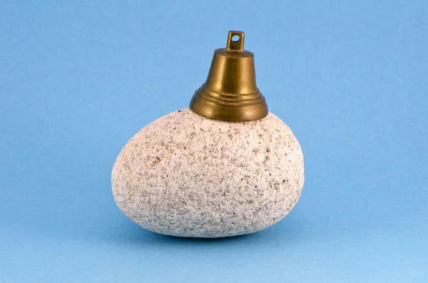Natural granite stone and brass bell on blue background — Stock Photo, Image