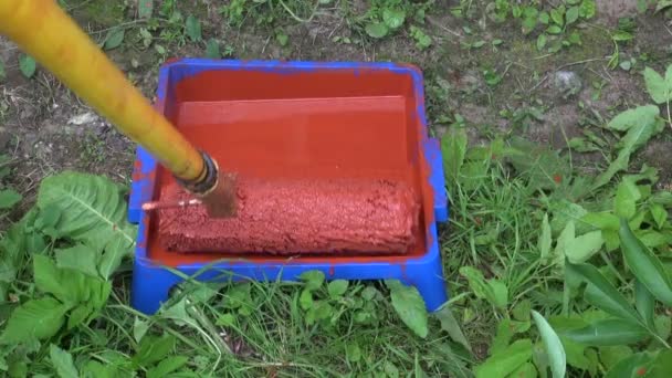 Rodillo de pintura en lata de pintura con pintura roja — Vídeos de Stock