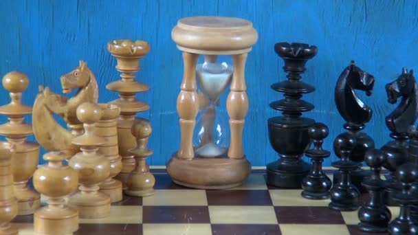 Trä schackpjäser på schackbrädet och timglas — Stockvideo