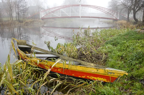 Färgglada gamla båt och river med bron i höst dimma — Stockfoto