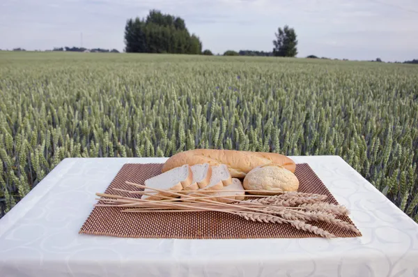 Bílý chléb na stůl a letní pšeničné pole — Stock fotografie