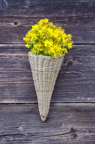 Wicker basket on old farm house wall with St Johns wort flowers — Stock Photo, Image