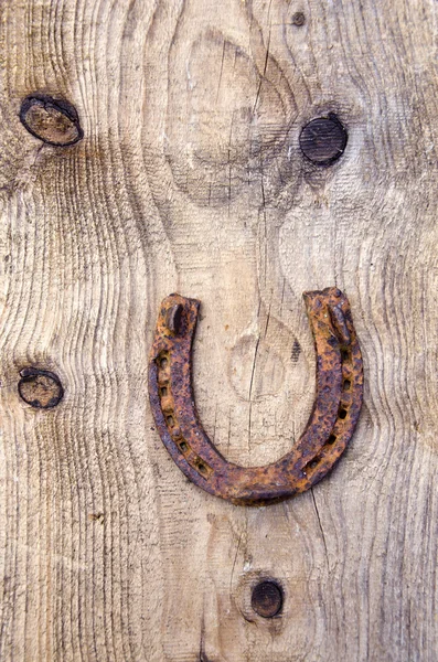 古い木の板の背景で古代のさびたホースシュー — ストック写真