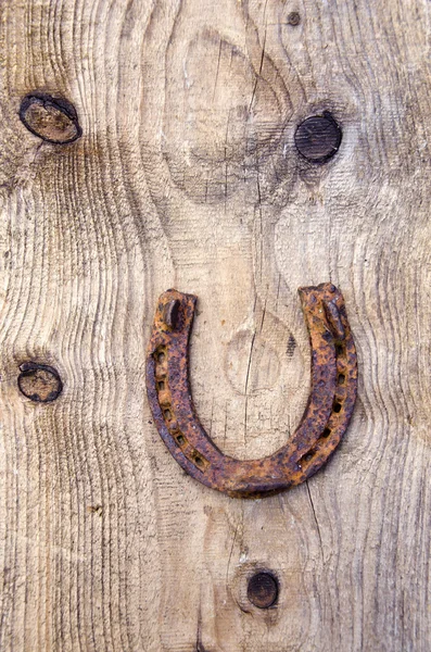 Oude roestige hoefijzer op oude houten plank achtergrond — Stockfoto