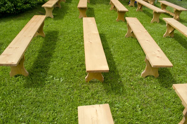 Beaucoup de nouveaux sièges en bois sur l'herbe — Photo