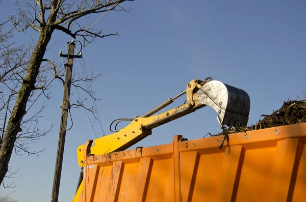 Excavator loading soil into dumper truck — Stock Photo, Image