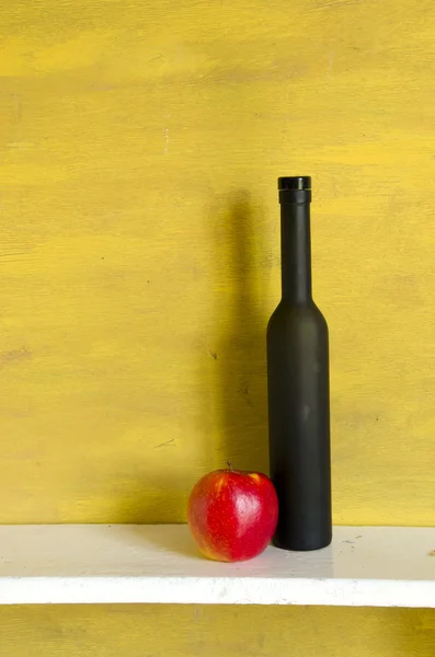 Zwarte fles wijn en rode appel — Stockfoto