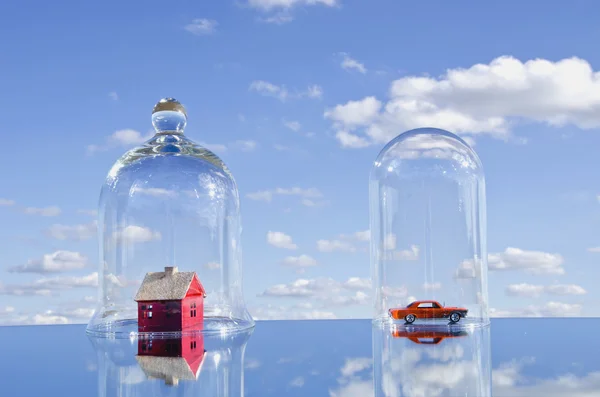 Casa y coche juguetes símbolos en campana de cristal —  Fotos de Stock