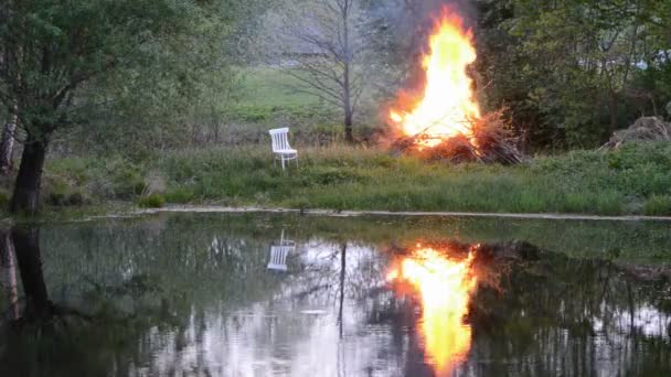 Lente brand in boerderij in de buurt van de vijver en wit stoel — Stockvideo