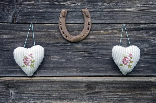 Corazones de tela en la pared de madera y herradura — Foto de Stock