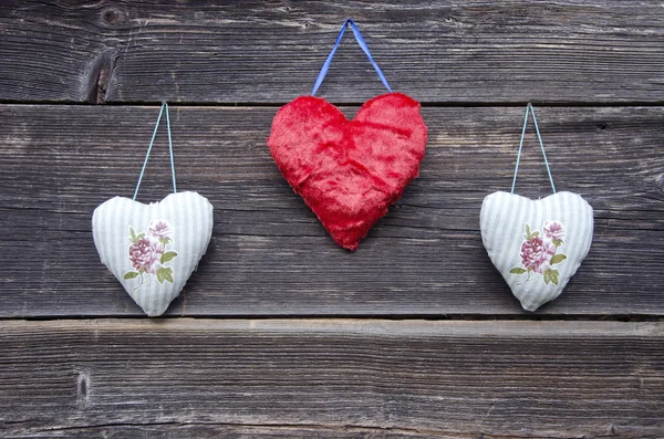Trois symboles de coeur en tissu sur vieux mur en bois — Photo