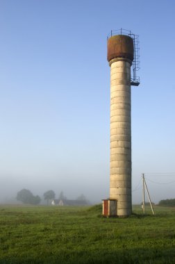 Beton eski su kulesi, kırsal sisli sabah yatay