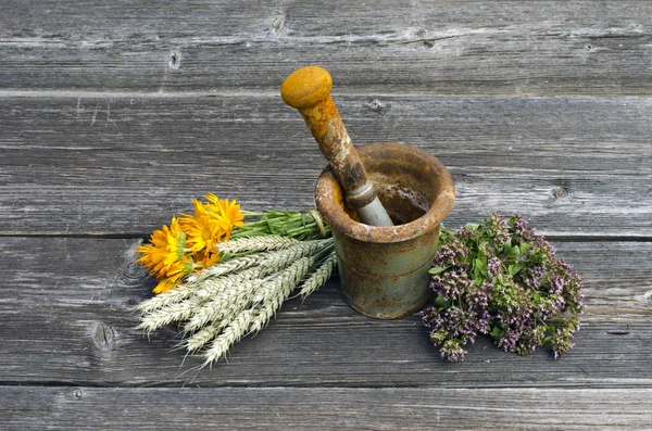 Ancient rusty iron mortar and medical herbs on old wooden background — Stock Photo, Image