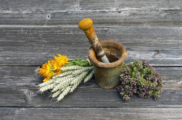 Antiguo mortero de hierro oxidado y hierbas medicinales sobre fondo de madera viejo — Foto de Stock