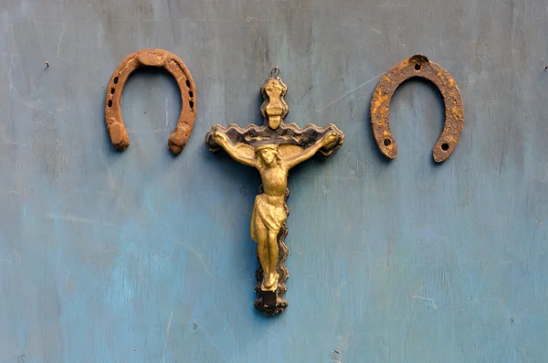 Sufrimiento de Jesucristo y dos herraduras oxidadas en la pared de madera azul —  Fotos de Stock