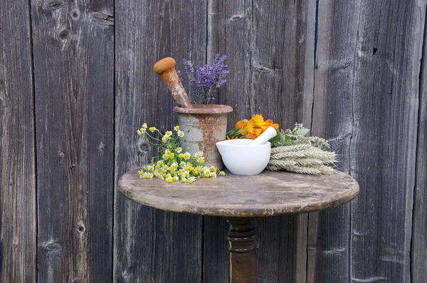 Ancient rusty iron mortar and medical herbs on old wooden table — Stock Photo, Image