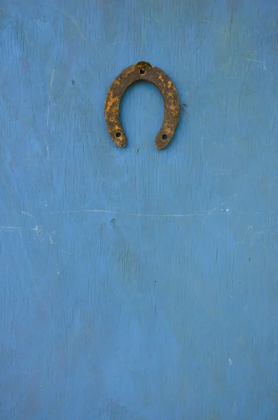 Simbol keberuntungan tua tapal kuda berkarat di dinding biru — Stok Foto