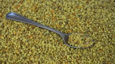 Rotating fresh ecological bee pollen granules background with spoon
