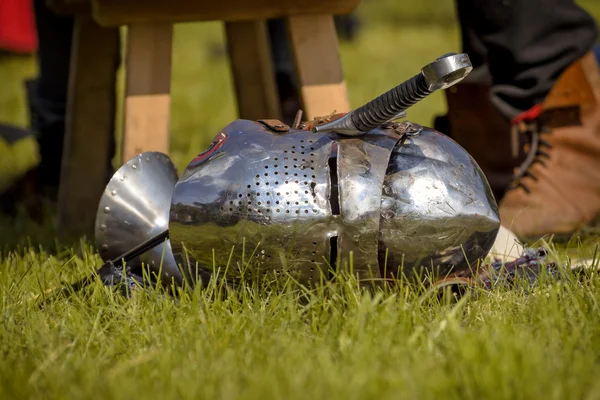 Helmet of the medieval knight and the sword on the green field. — Stock Photo, Image