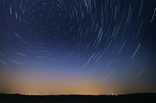 Startrail krajina pohybu hvězd v noční obloze nad městem — Stock fotografie