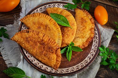 Geleneksel Kırım Tatar mutfağı, tavuk etli chebureki. Ahşap arka planda kızarmış börekler.