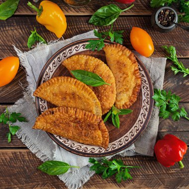 Geleneksel Kırım Tatar mutfağı, tavuk etli chebureki. Ahşap arka planda kızarmış börekler.