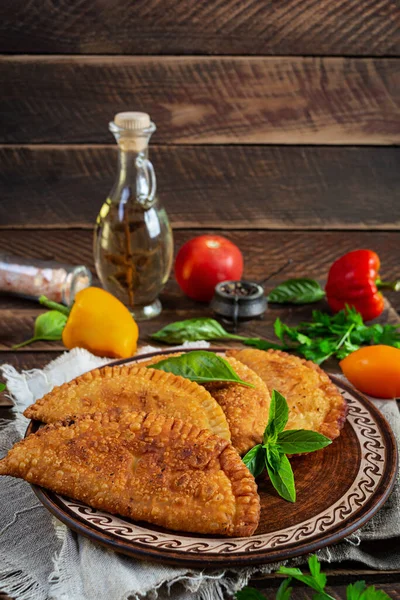 Geleneksel Kırım Tatar mutfağı, tavuk etli chebureki. Ahşap arka planda kızarmış börekler.