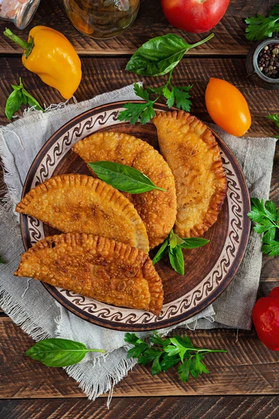 Geleneksel Kırım Tatar mutfağı, tavuk etli chebureki. Ahşap arka planda kızarmış börekler.