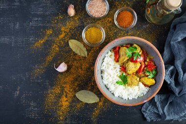 Baharatlı körili tavuk ve pilav. Koyu arkaplanda tavuk ve pilav ile köri sosu. Üst görünüm