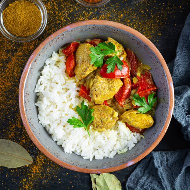 Baharatlı körili tavuk ve pilav. Koyu arkaplanda tavuk ve pilav ile köri sosu. Üst görünüm