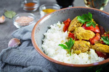 Baharatlı körili tavuk ve pilav. Gri arka planda tavuk ve pilav ile köri sosu