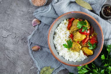 Baharatlı körili tavuk ve pilav. Gri arka planda tavuk ve pilav ile köri sosu. Üst görünüm