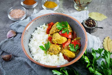 Baharatlı körili tavuk ve pilav. Gri arka planda tavuk ve pilav ile köri sosu