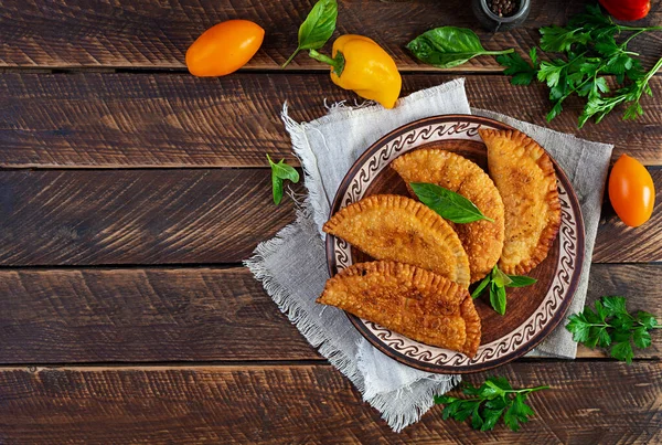 Geleneksel Kırım Tatar mutfağı, tavuk etli chebureki. Ahşap arka planda kızarmış börekler.