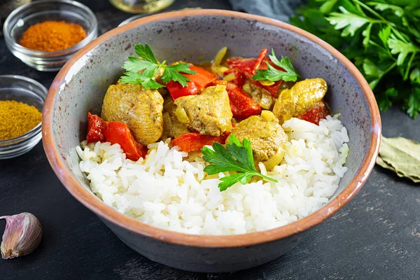 Baharatlı körili tavuk ve pilav. Koyu arkaplanda tavuk ve pilav ile köri sosu.