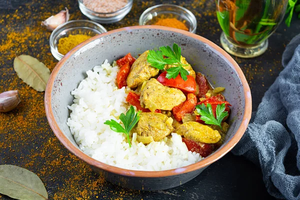 Baharatlı körili tavuk ve pilav. Koyu arkaplanda tavuk ve pilav ile köri sosu.