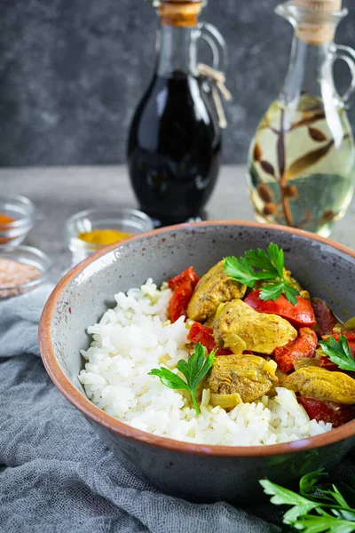 Baharatlı körili tavuk ve pilav. Gri arka planda tavuk ve pilav ile köri sosu