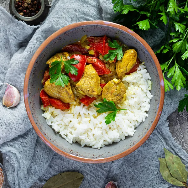 Baharatlı körili tavuk ve pilav. Gri arka planda tavuk ve pilav ile köri sosu. Üst görünüm