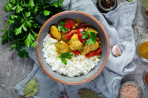 Baharatlı körili tavuk ve pilav. Gri arka planda tavuk ve pilav ile köri sosu. Üst görünüm