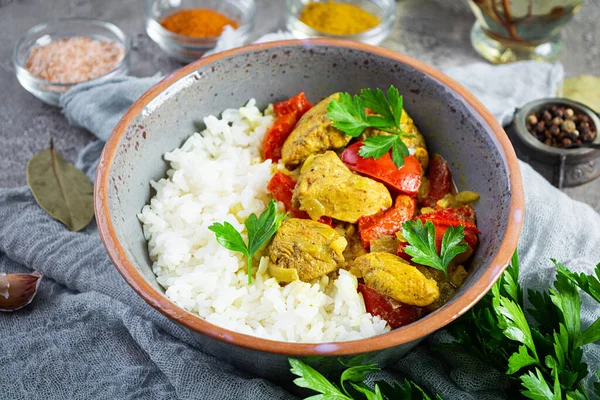 Baharatlı körili tavuk ve pilav. Gri arka planda tavuk ve pilav ile köri sosu