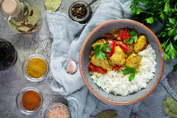 Baharatlı körili tavuk ve pilav. Gri arka planda tavuk ve pilav ile köri sosu. Üst görünüm