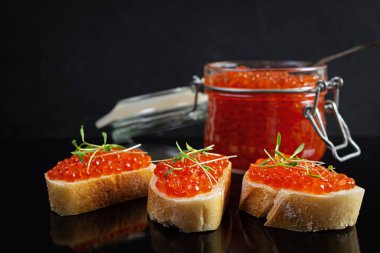 Siyah arka planda baget ekmekli lezzetli kırmızı havyar.