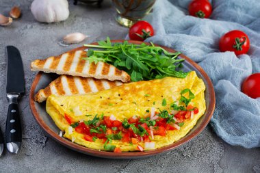 Fried omelette with tomatoes, onion and herbs. Delicious breakfast with eggs and toasts