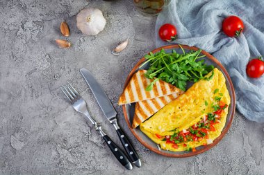 Fried omelette with tomatoes, onion and herbs. Delicious breakfast with eggs and toasts. Top view