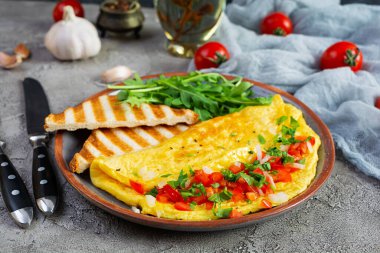 Fried omelette with tomatoes, onion and herbs. Delicious breakfast with eggs and toasts