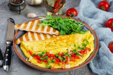 Fried omelette with tomatoes, onion and herbs. Delicious breakfast with eggs and toasts