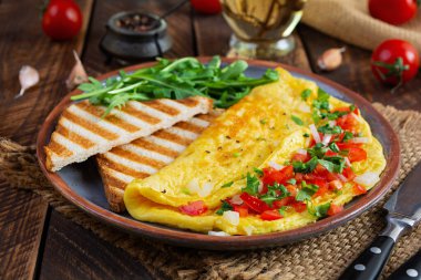 Fried omelette with tomatoes, onion and herbs. Delicious breakfast with eggs and toasts