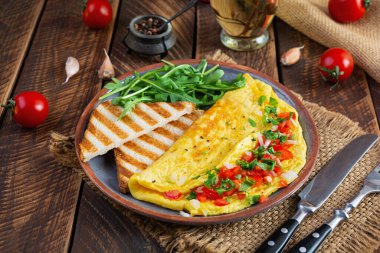 Fried omelette with tomatoes, onion and herbs. Delicious breakfast with eggs and toasts